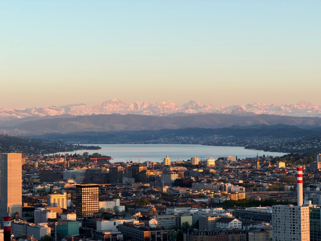 Stunning aerial view of Zürich cityscape with Lake Zürich and the Alps in the background.